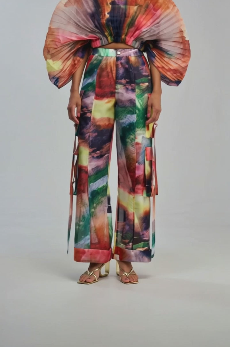 Video of a woman modeling the Watercolors Chiffon Cargo Pant, a loose, high-waisted pant featuring a watercolor print and side pockets.