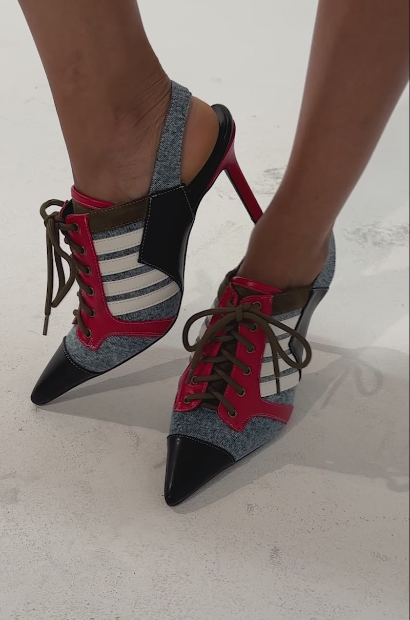 Video of a woman modeling the AZALEA WANG GENISIS MULTI SPORTY SLING BACK PUMP—pointed-toe, lace-up high heels featuring vibrant red, blue, black, and white accents and a striking stiletto heel for a sporty-chic look.
