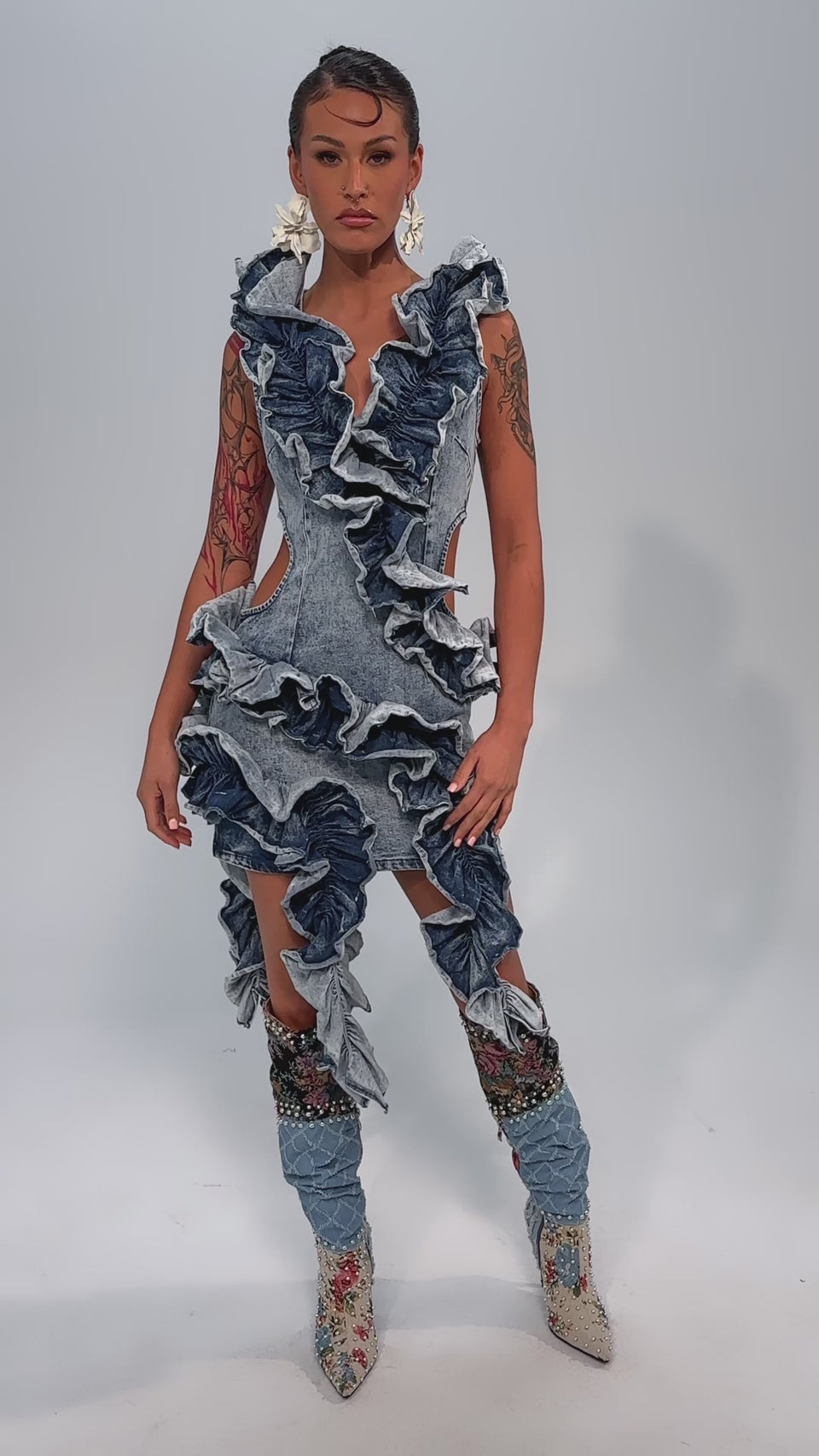 Video of woman modeling the SAY IT AGAIN RUFFLED DENIM MINI DRESS, paired with matching denim leg boots and floral earrings.