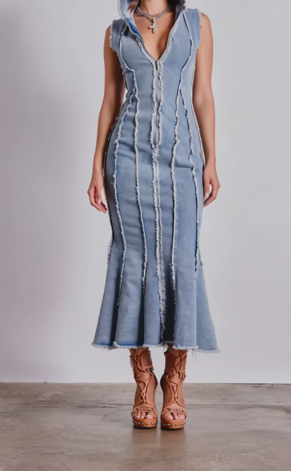 A video of a woman in the CATCH MY SWAG DENIM HOODED MAXI DRESS—a sleeveless, form-fitting, light wash maxi dress with frayed seams and a deep V-neck.