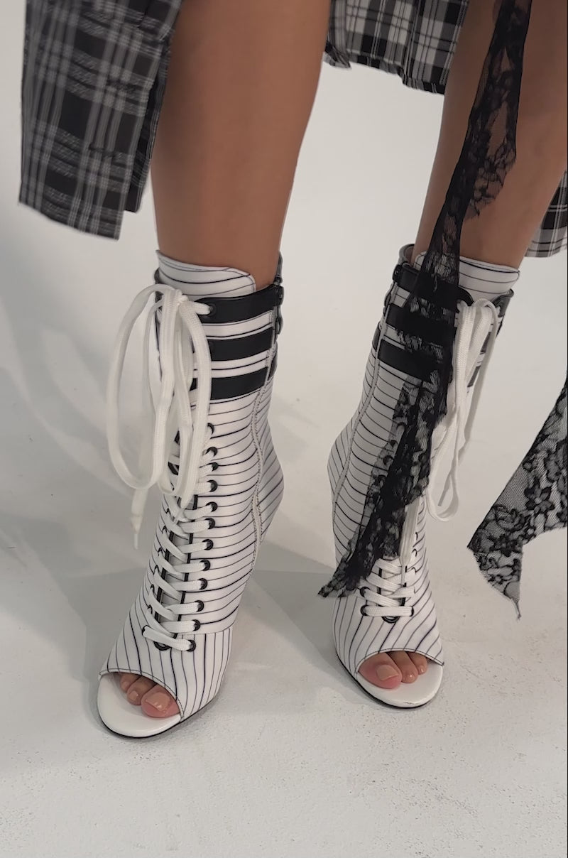 A video of a person wearing the AZALEA WANG WYATT WHITE STRIPED NAUTICAL OPEN TOE BOOTIE.