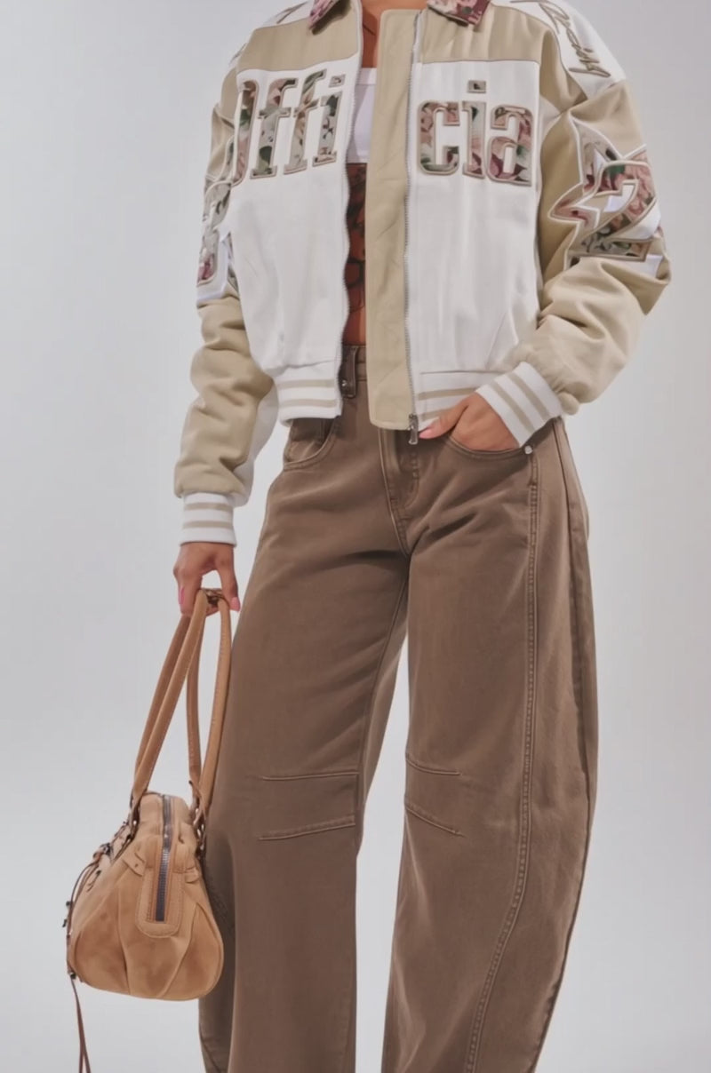 Video of woman modeling the STILL THE ONE EMBROIDERED BOMBER stands with one hand adjusting her glasses against a light background.