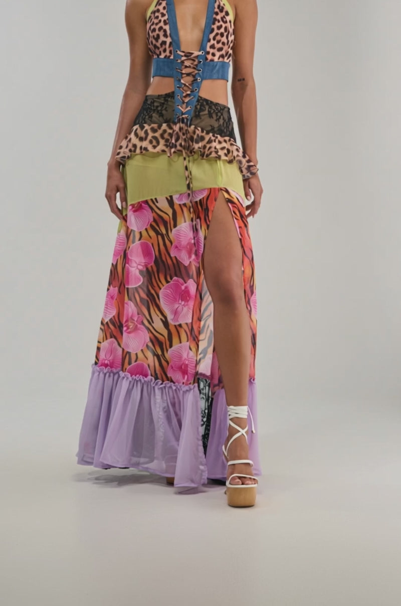 Video of a woman modeling the SUPER SWEET GIRL PATTERNED MAXI DRESS—a bold statement piece with a leopard print halter top, lace-up front, mixed patterns, green and leopard skirt layers, pink floral accents, lavender ruffle hem.