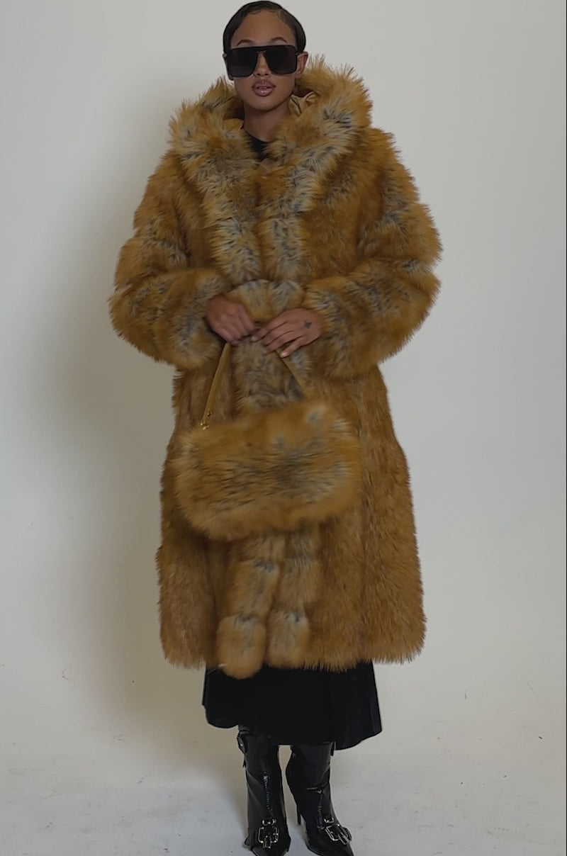 Video of woman modeling the OLD MONEY FAUX FUR COAT, with large sunglasses, stands against a plain background, holding a matching round fur handbag 