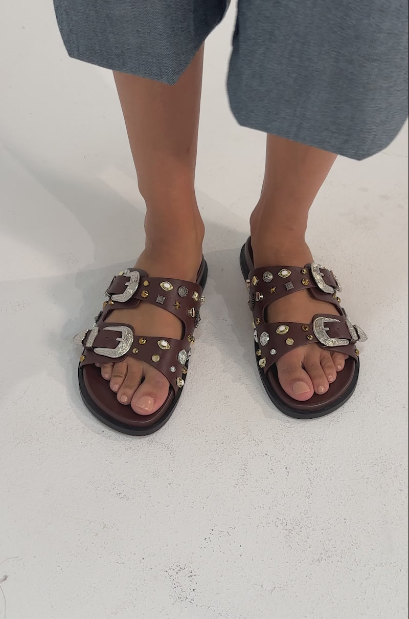 A video of a model wearing  the AKIRA BARCLAY BROWN METAL EMBELLISHED SLIP ON FLAT SANDAL.