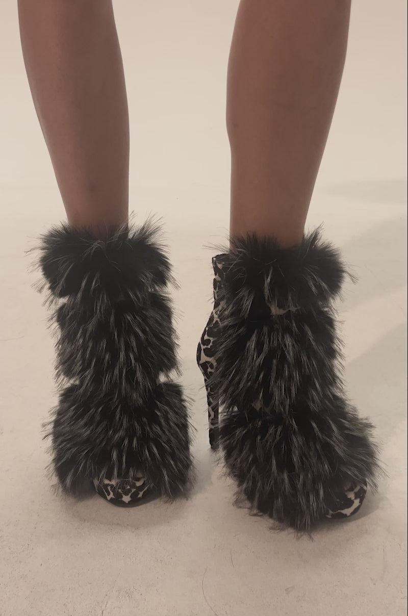 Video of woman modeling the AZALEA WANG SERIOUS Black and White Leopard with Fur Open Toe Stiletto Bootie featuring a platform sole, an animal print, and thick black faux fur trim