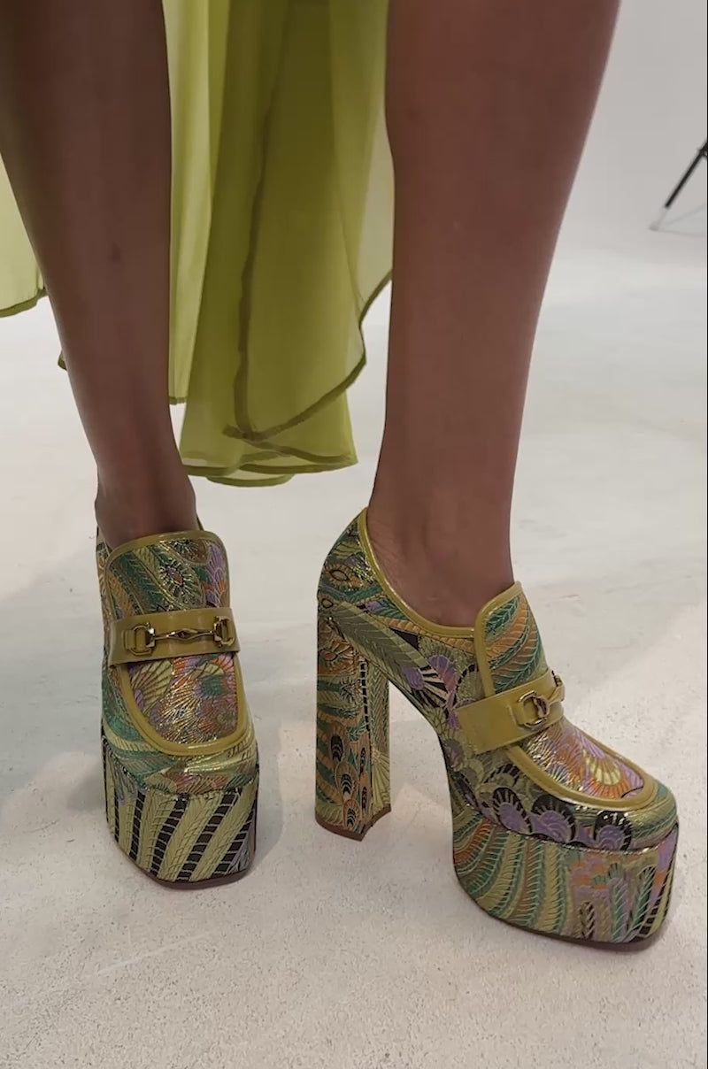 Video of woman modeling the AZALEA WANG JUSTLY GREEN MULTI PLATFORM BROCADE BLOCK HEEL PUMP, which features a vibrant embroidered pattern and gold buckle details