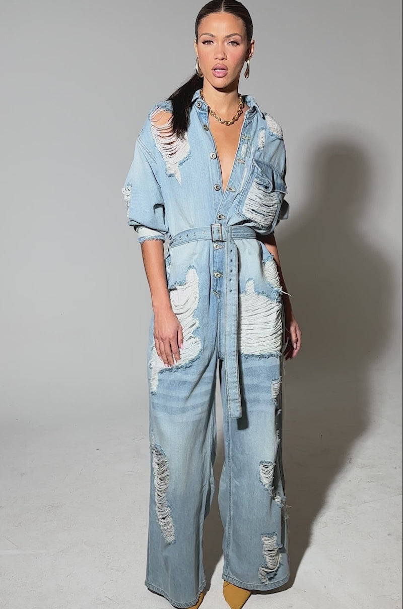 Video of woman modeling the NOT TODAY EXTREME OVERSIZED DISTRESSED DENIM JUMPSUIT with wide legs and heavy rips, paired with yellow pointed-toe shoes, against a plain background.