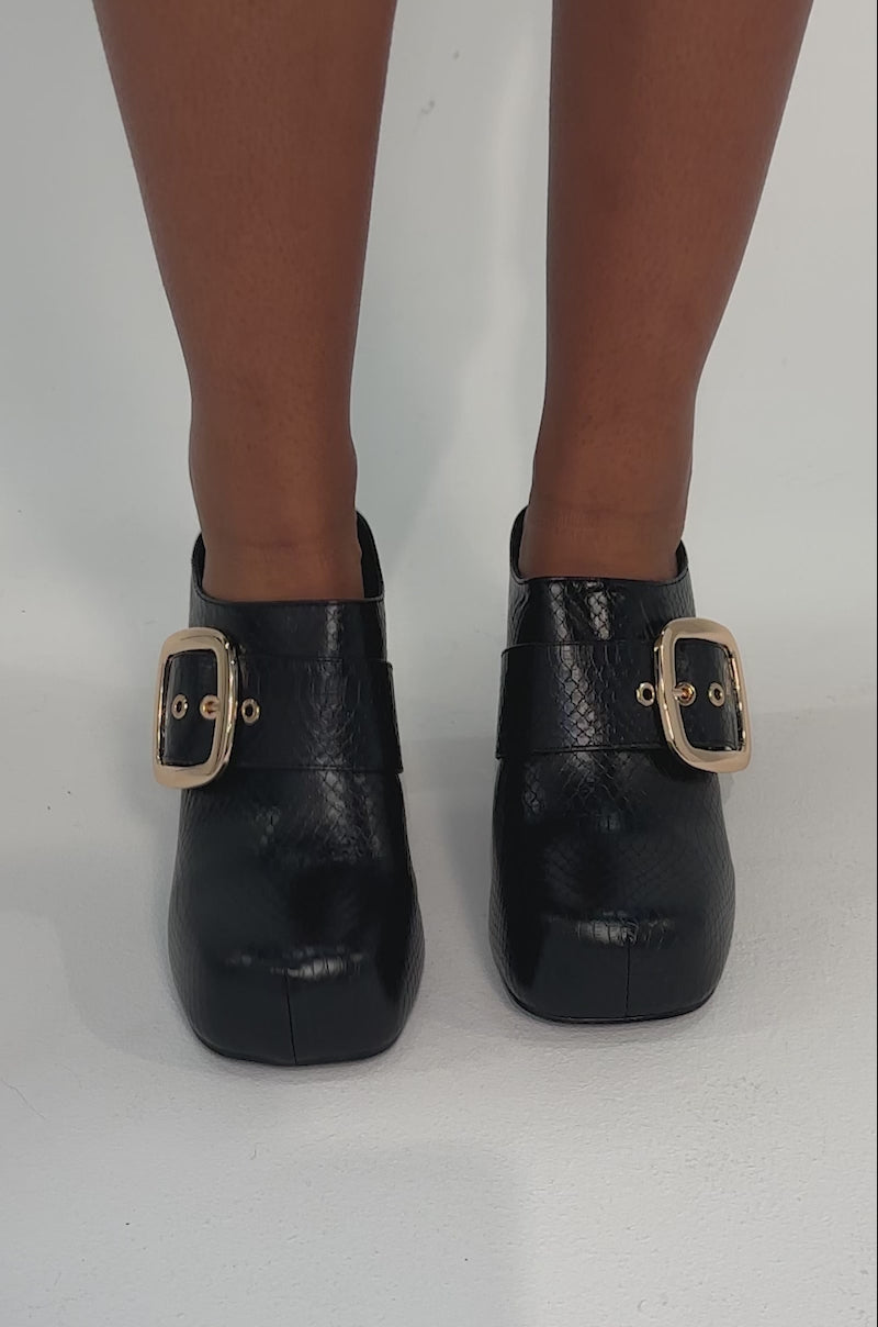 Video of woman modeling the AZALEA WANG ELYSIA BLACK PU ROUND TOE MULE, featuring a textured faux leather finish and large gold buckles