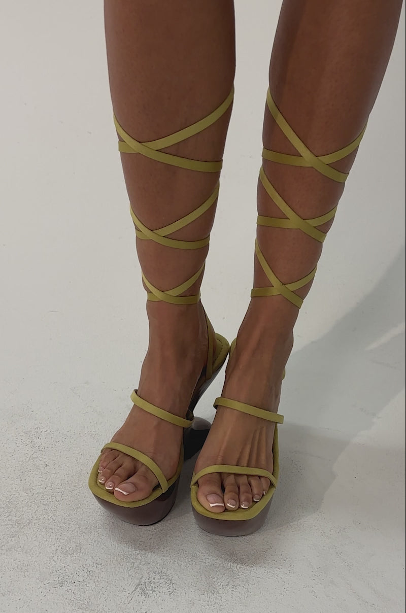 Video of woman modeling the AZALEA WANG ONNI CITRON WEDGE SANDALS—strappy yellow lace-up sandals with chunky brown wooden heels—against a plain light background.