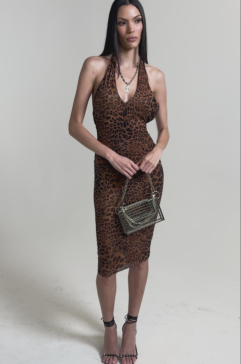 A video of a woman wearing the WALK ON THE WILD SIDE LEOPARD PRINT MIDI DRESS featuring a halter neck, bodycon fit, and ruched details. 