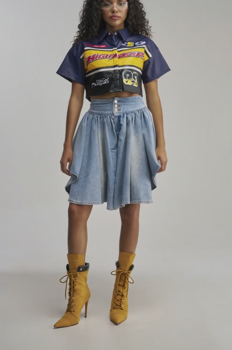 Video of woman modeling the COOLEST GAUCHO PANT—a blue, high-waisted, button-front denim piece with draped sides reminiscent of light wash gauchos—paired with brown lace-up high heel boots