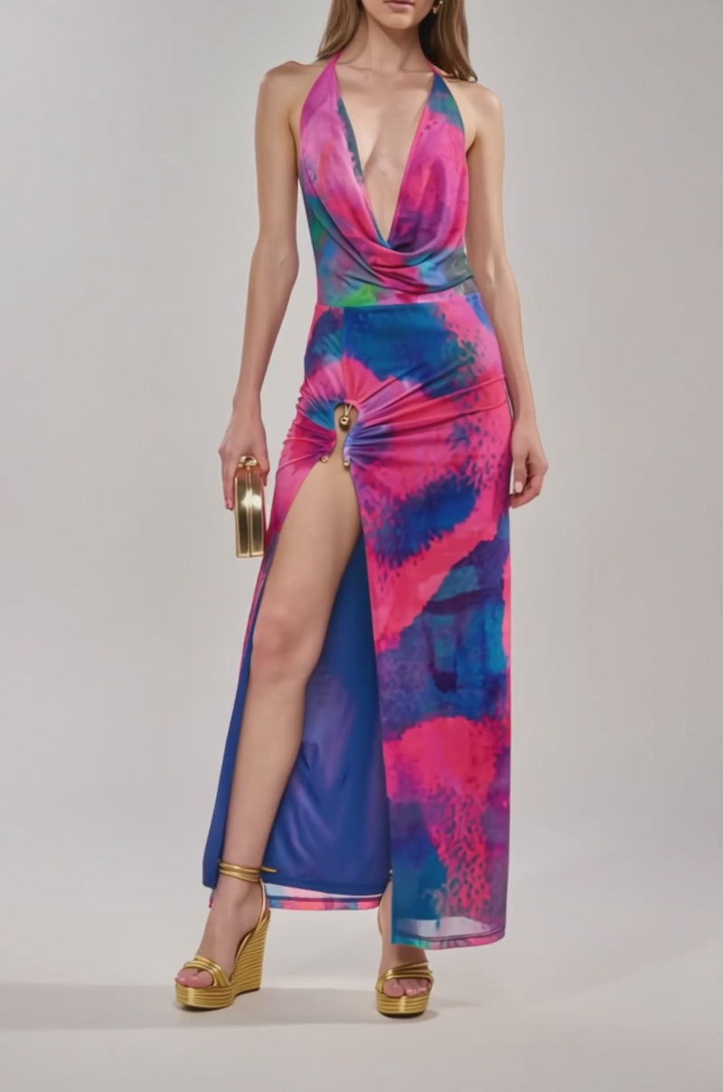 Video of woman modeling the ARTISTS MUSE MAXI DRESS—a vibrant tropical print with pink, blue, and purple patterns, cowl neckline, high slit with ring