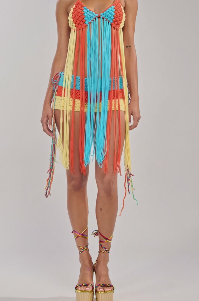 Video of woman modeling the BEACHIN CROCHET BRALETTE IN ORANGE, styled with fringe details, matching platform sandals, and hoop earrings for a playful festival look against a simple light background.