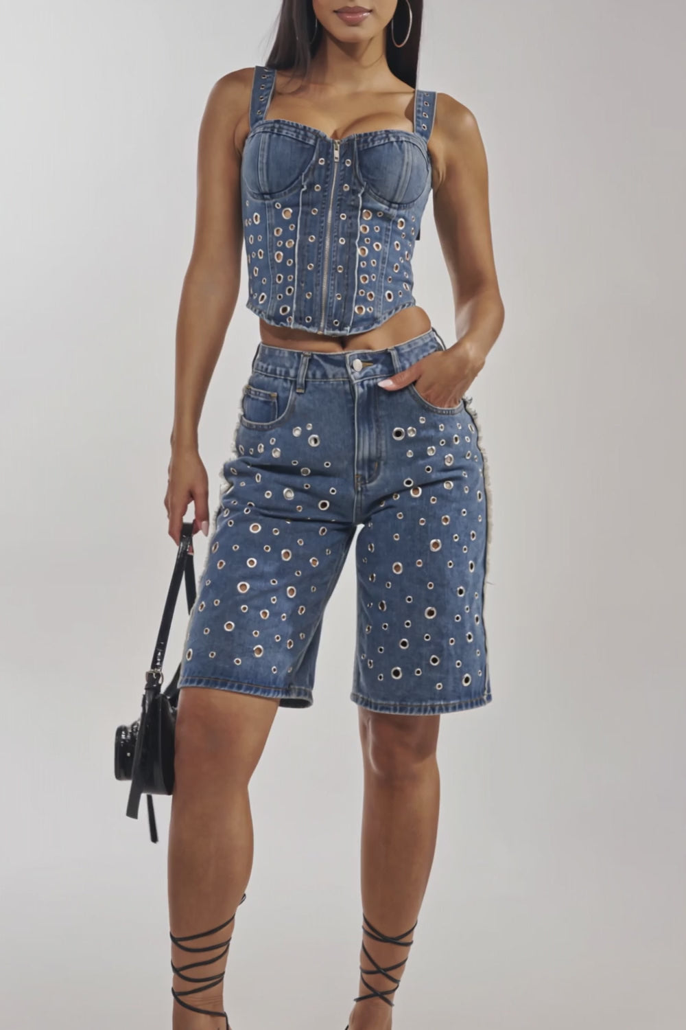 Video of woman modeling the TAYLOR DENIM CORSET WITH GROMMET, featuring a sweetheart neckline and silver hardware, paired with matching jean shorts. 