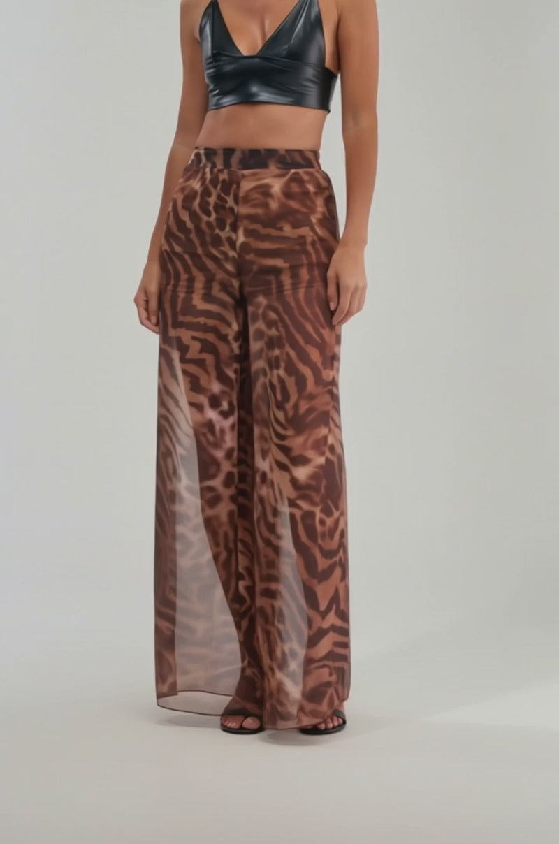 A video of a person wearing the MOONLIGHT TIGER PALAZZO PANTS—sheer, wide-leg pants with a brown and black tiger stripe pattern over matching shorts. 