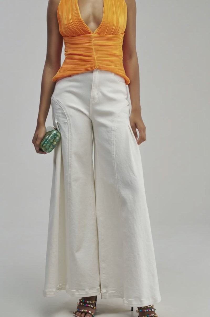 Video of a woman modeling the SHOWBIZ BABY BLOUSE IN ORANGE—a vibrant pleated satin halter top ideal for summer date nights or as a chic vacation blouse.