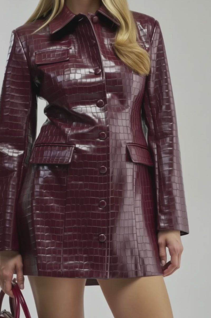 Video of a woman modeling the ALWAYS IN CHARGE PU MINI DRESS IN BURGUNDY, a shiny croc-embossed mini dress with long sleeves.