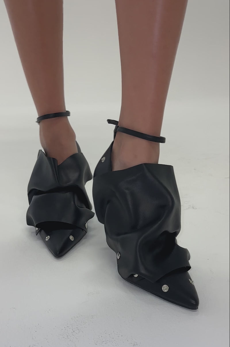 Video of woman modeling the AZALEA WANG IMOGALE Black Silver Hardware Stiletto Pump featuring black pointed toes, ruched faux leather, metal rivet details, and thin ankle straps