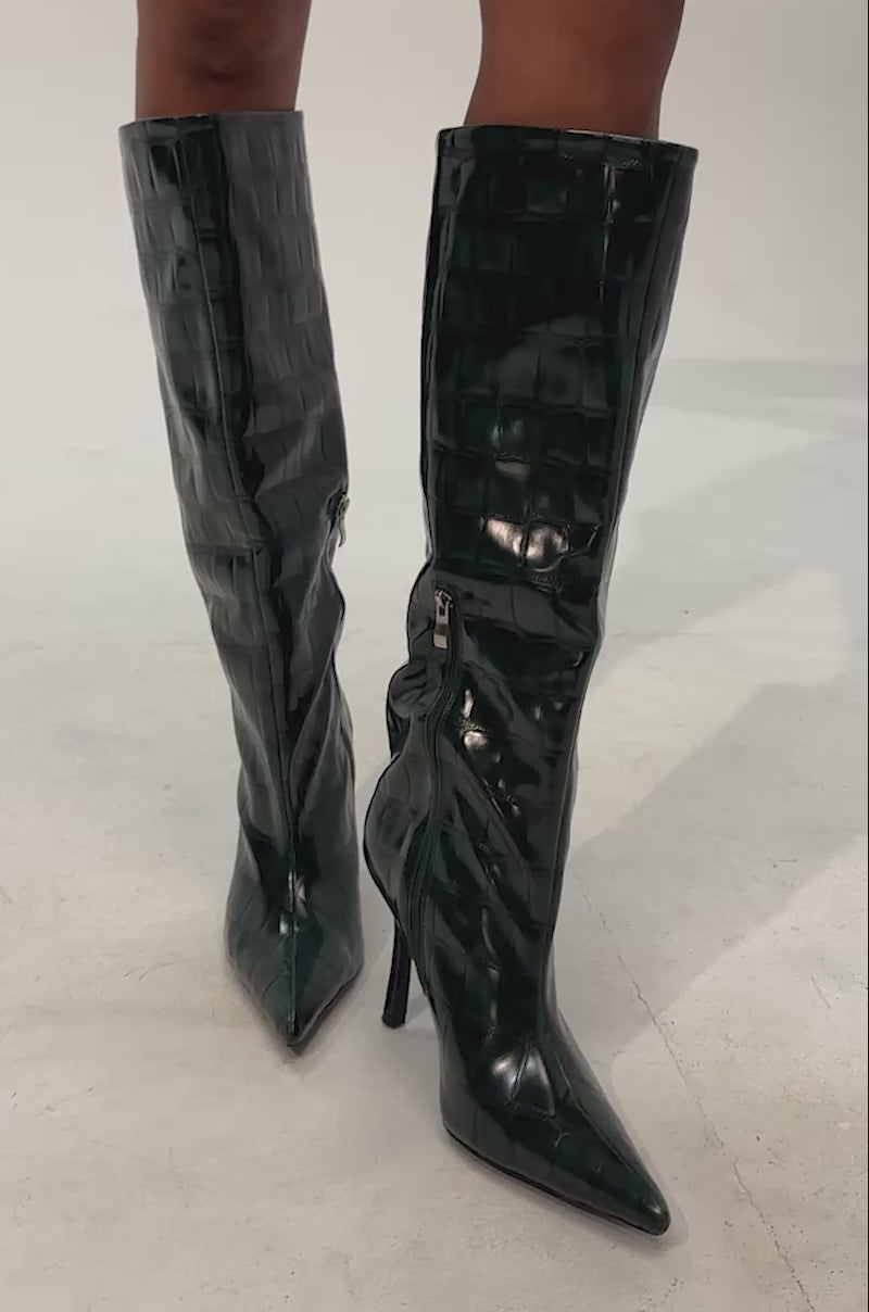 Video of woman modeling the AZALEA WANG FLOREN DARK GREEN CROC STILETTO BOOTS—these knee-high boots feature an embossed crocodile print in dark green, pointed toes, stiletto heels, and side zippers