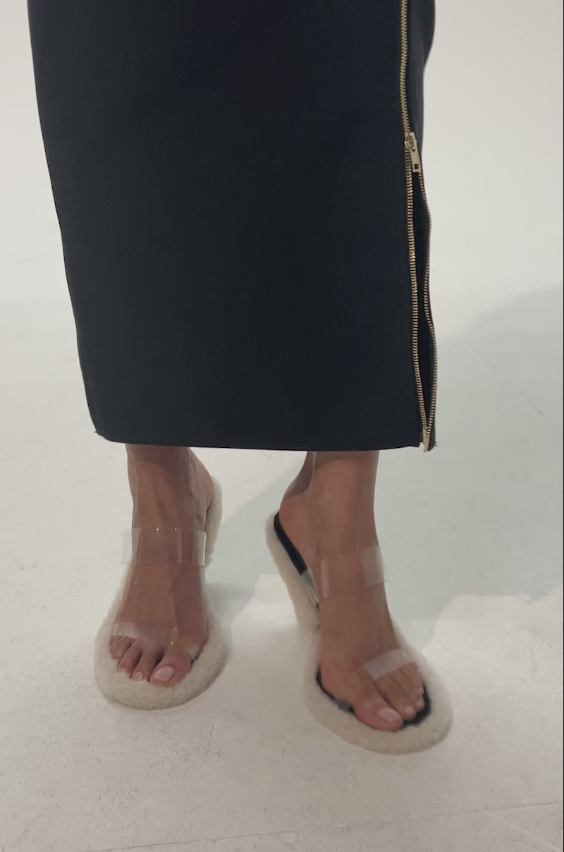 Video of woman modeling the AKIRA GOLD LITTY CLEAR SHERPA LINED SANDAL, featuring clear straps and fuzzy cream-colored soles, shown against a plain background.