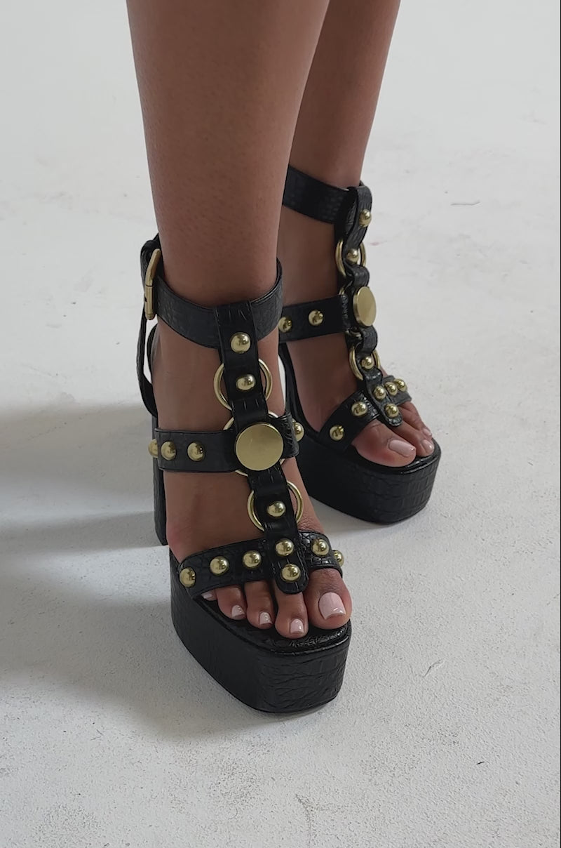 A video of a person wearing AZALEA WANG ELSU Black Croc Embossed Platform Sandals with block heels, gold studs, and buckles.