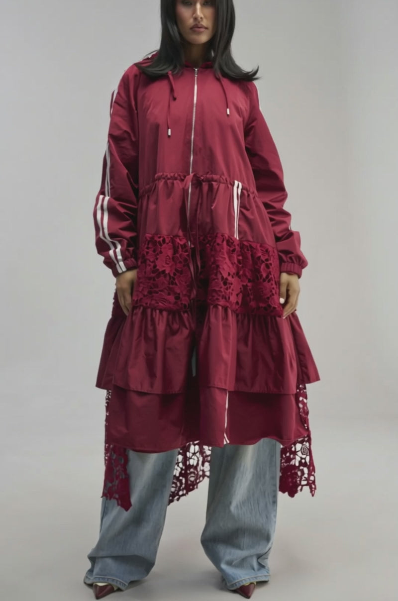 Video of a woman modeling the READY FOR IT TRENCH, a long burgundy trench coat with intricate lace detailing, layered over a white lace bralette.