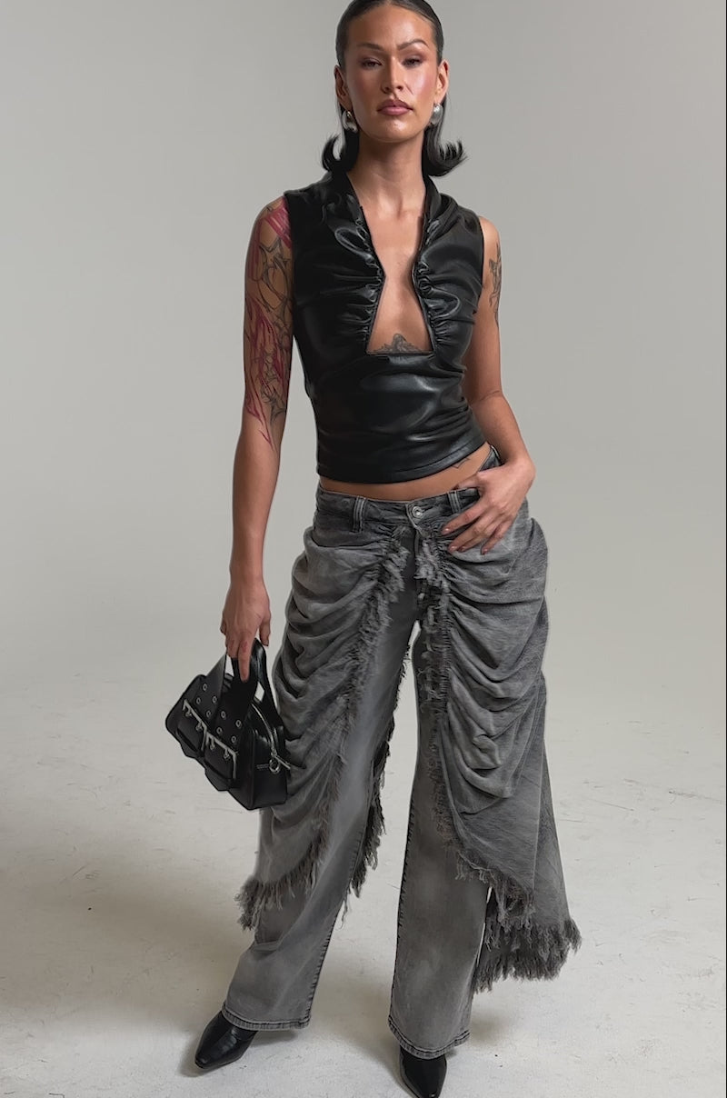 A video of model in a black sleeveless vinyl top and WOW WOW WOW DENIM PANT, styled with dramatic ruching and frayed details. 