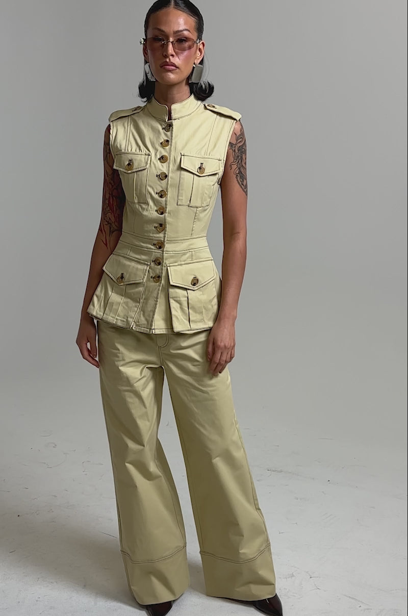 A video of a woman in the DIANA VEST TOP and wide-leg khaki pants standing confidently against a light gray background.
