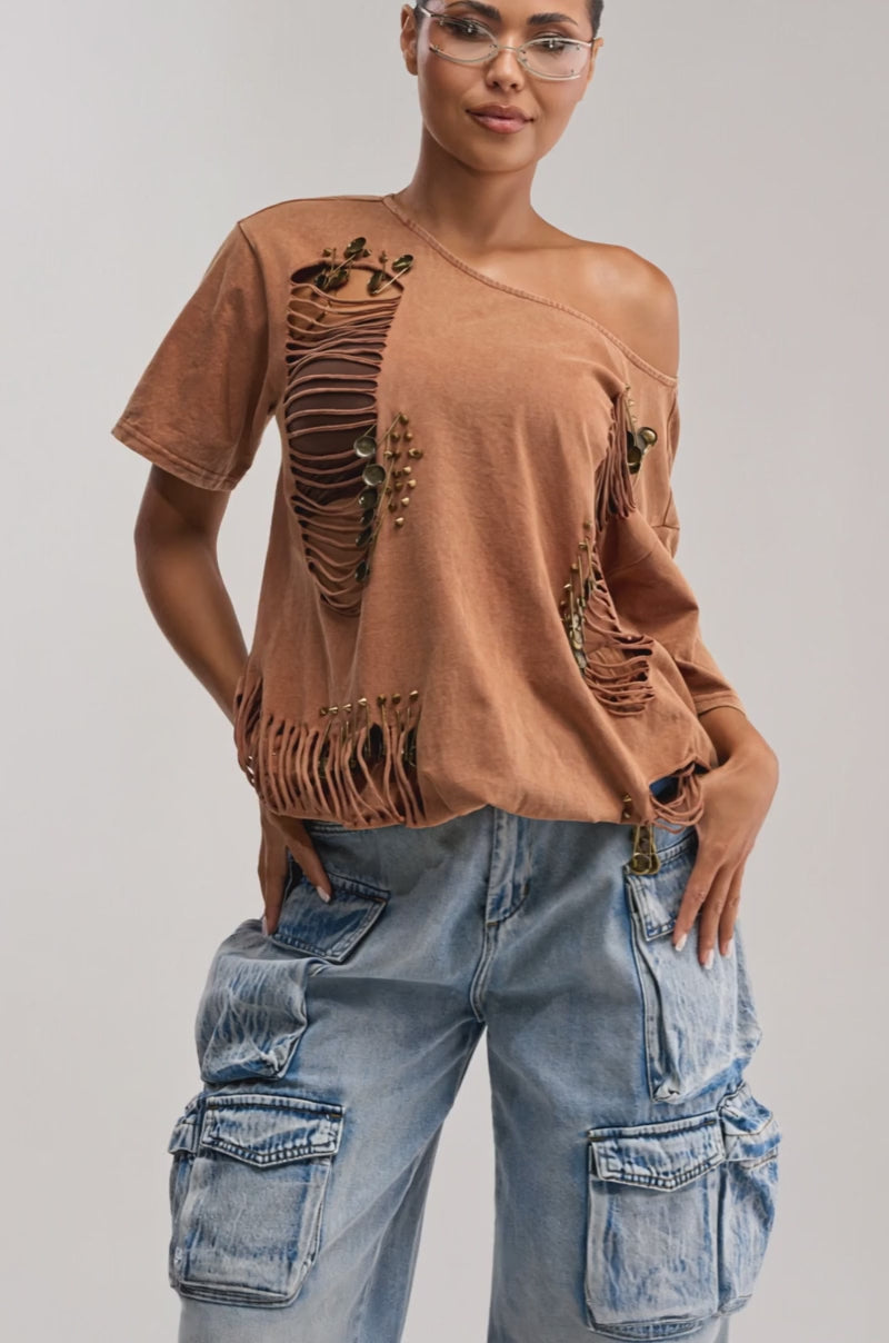 Video of woman modeling the IN THE CUT DISTRESSED TEE with shredded paneling and cutout details, teamed with clear glasses and loose blue cargo jeans, posing confidently against a neutral background.