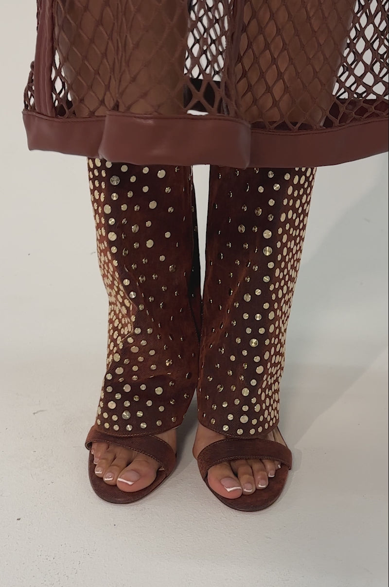 Video of woman modeling the AKIRA GOLD RAYSSA BURNT ORANGE GOLD HARDWARE EMBELLISHED STILETTO SANDALS. Gold jewelry and a textured gold clutch complete the look