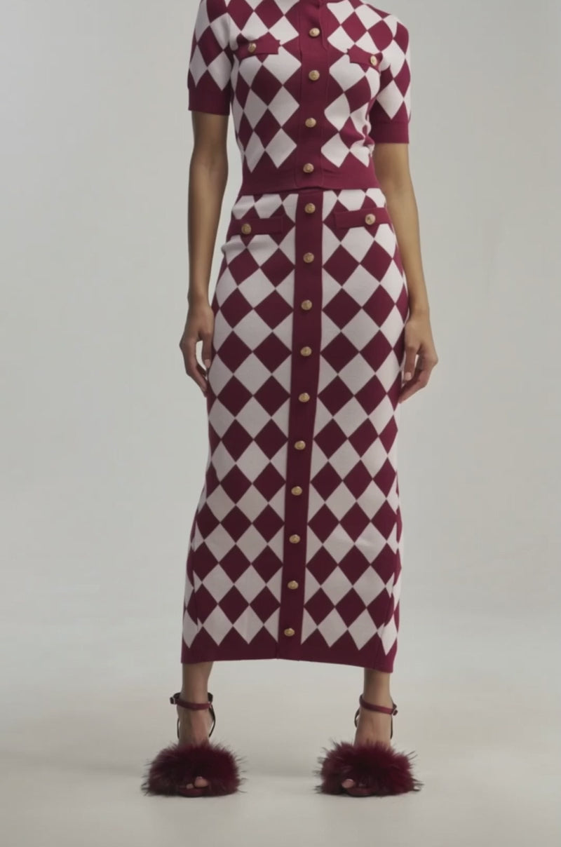 Video of a woman modeling the SWEET BABY GIRL MIDI SKIRT IN RED MULTI, which is a matching high-rise knit skirt with gold buttons. 