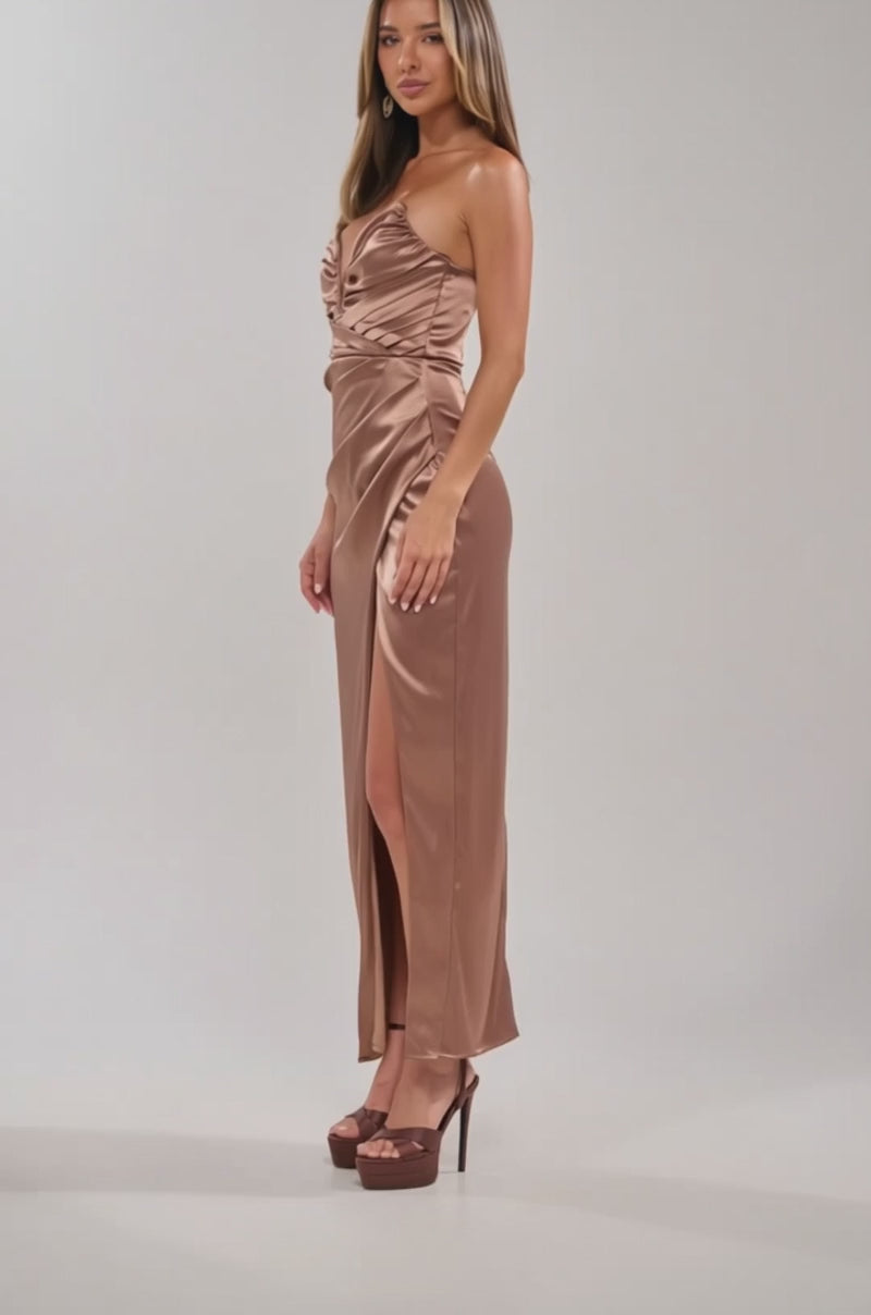 Video of woman modeling the HAVING A BALL SATIN MAXI DRESS IN BROWN, a shiny, strapless evening gown with a ruched bodice and thigh-high slit, styled with elegant high-heeled sandals against a light background.