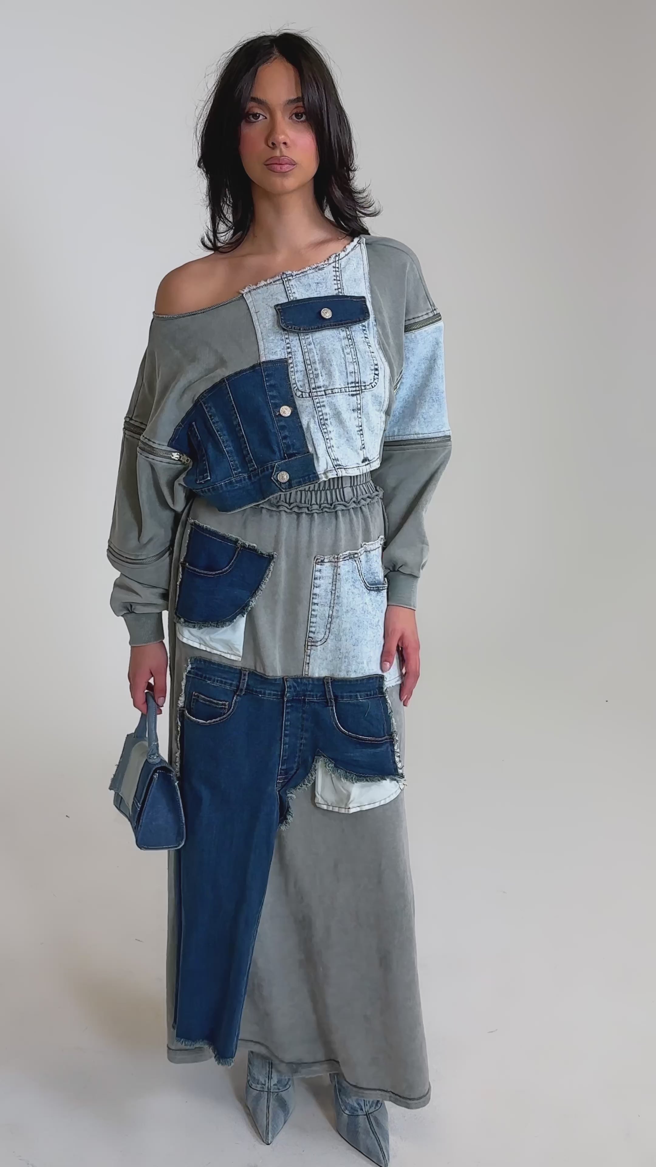 A video of a woman in the DENIM DREAMS ZIPPER DETAIL SWEATSHIRT with a matching denim patchwork maxi skirt, pointed-toe boots, and a patchwork clutch.
