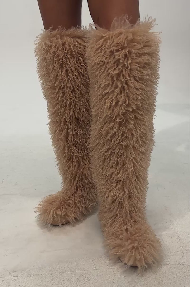 Video of woman modeling the AZALEA WANG TEMPLETON NUDE POODLE FUR OVER THE KNEE BOOT—tall, shaggy, tan faux poodle fur boots—paired with red leather shorts