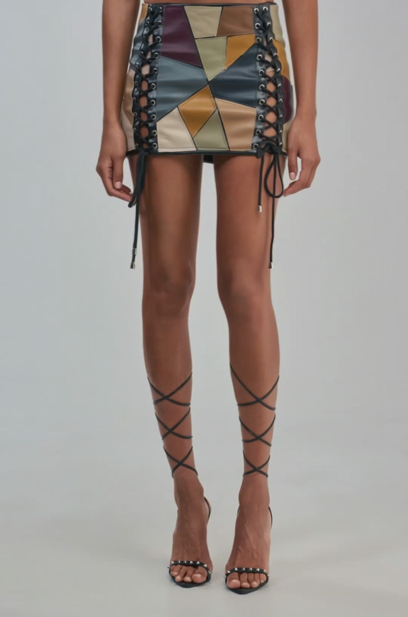 Video of a woman modeling the LACED UP FOR GOOD MINI SKIRT—a patchwork faux leather mini skirt featuring bold lace-up side detailing.