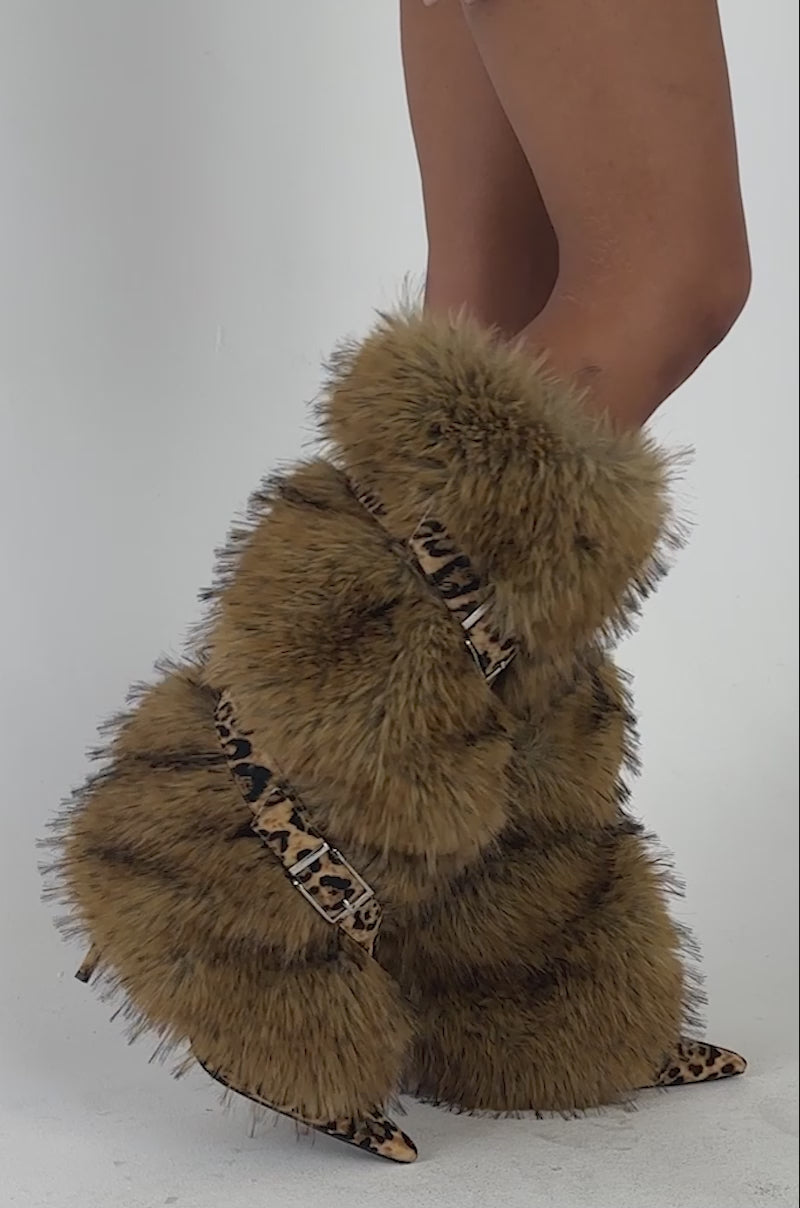Video of a woman modeling the AZALEA WANG NIRA LEOPARD FUR STILETTO BOOT—tall, brown furry boots with leopard print straps and high heels.