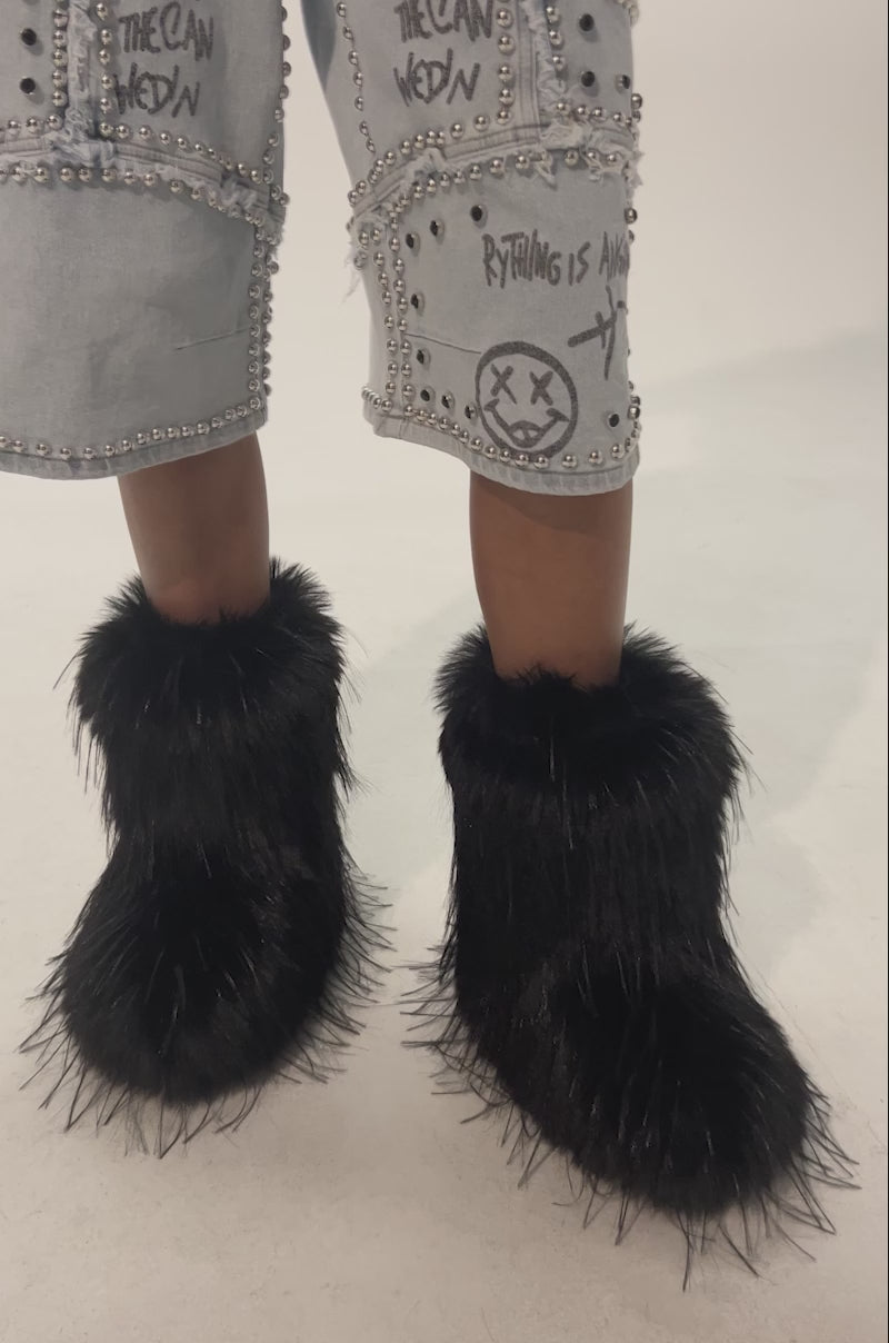 Video of woman modeling the AZALEA WANG LENIX BLACK FLAT FUR BOOTIEs, standing against a plain light background.