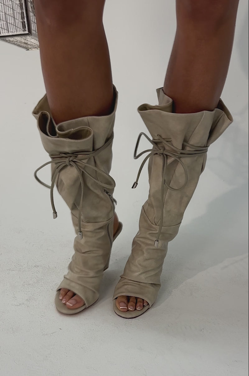 Video of woman modeling the AZALEA WANG VAILEN GREY OPEN TOE SLOUCHY BOOTIE, featuring a chic ruched design and drawstring details, set against a plain, light-colored background.