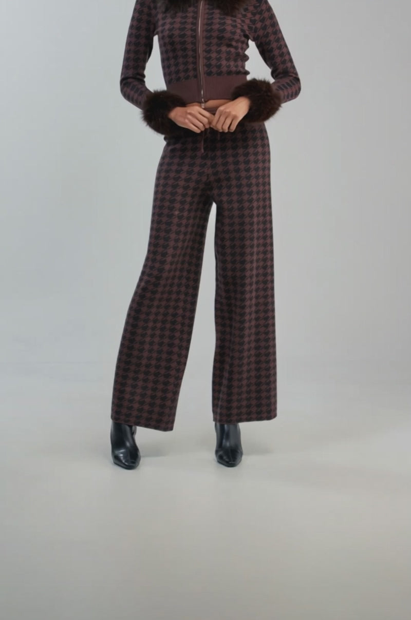 Video of a woman modeling the HIGH MAINTENANCE HOUNDSTOOTH PANT as part of a brown and black checkered matching set with wide-leg pants and faux fur trim on the cuffs and collar.