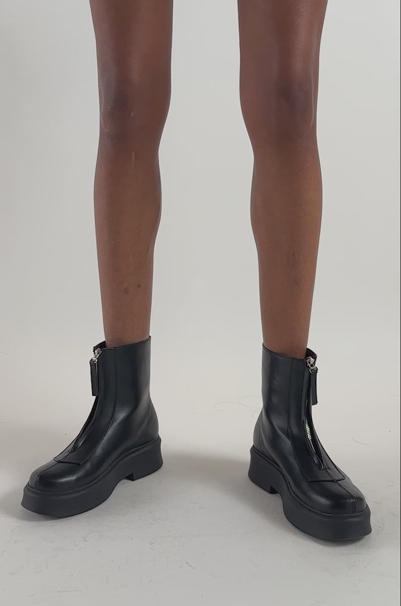 Video of a woman modeling the AZALEA WANG LATOYA BLACK PU ZIPPER EMBELLISHED COMBAT BOOTIE with chunky soles.