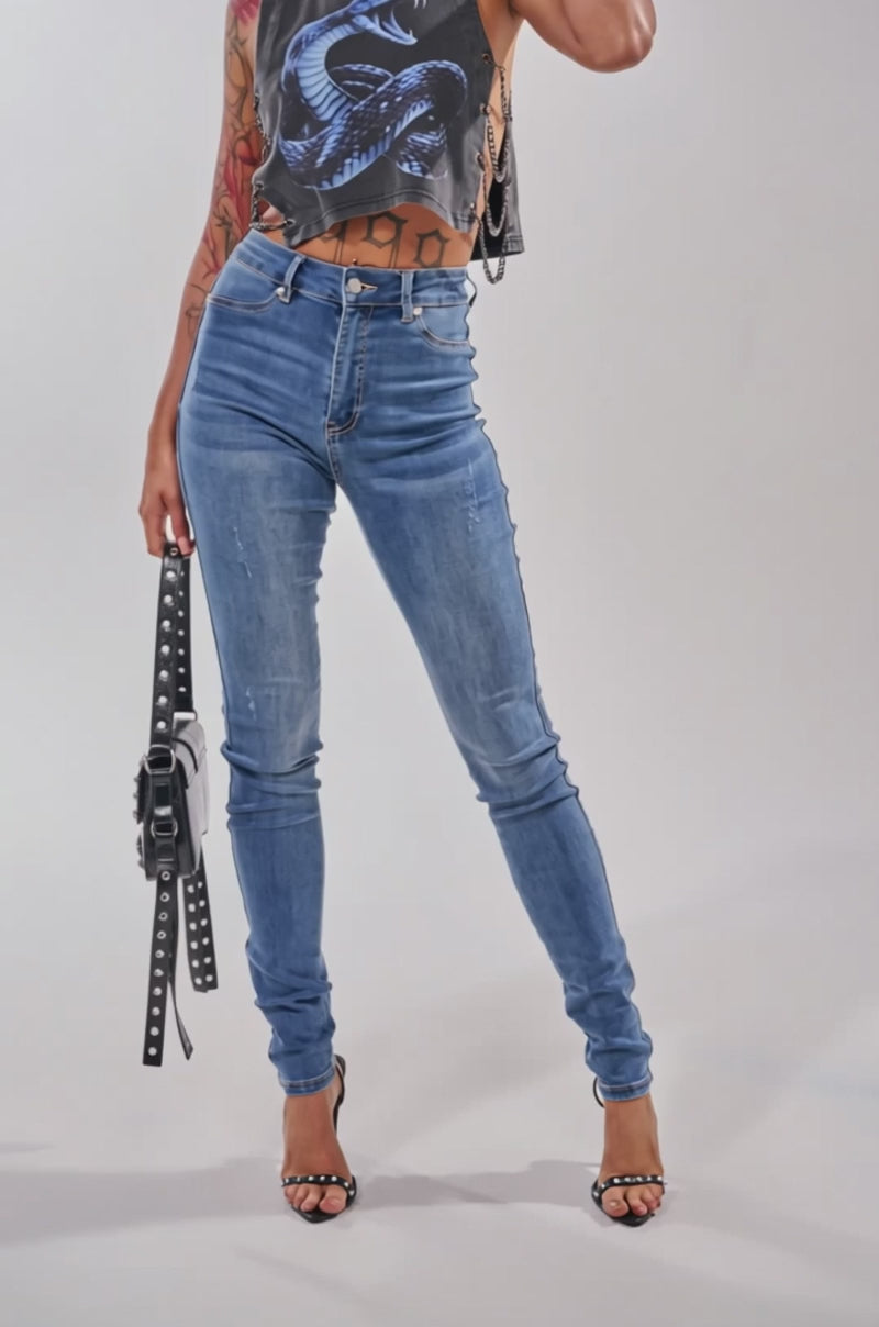 Video of woman modeling the FLEX-FIT HIGH WAISTED SUPER STRETCHY SKINNY JEANS, holding a small black and white handbag.