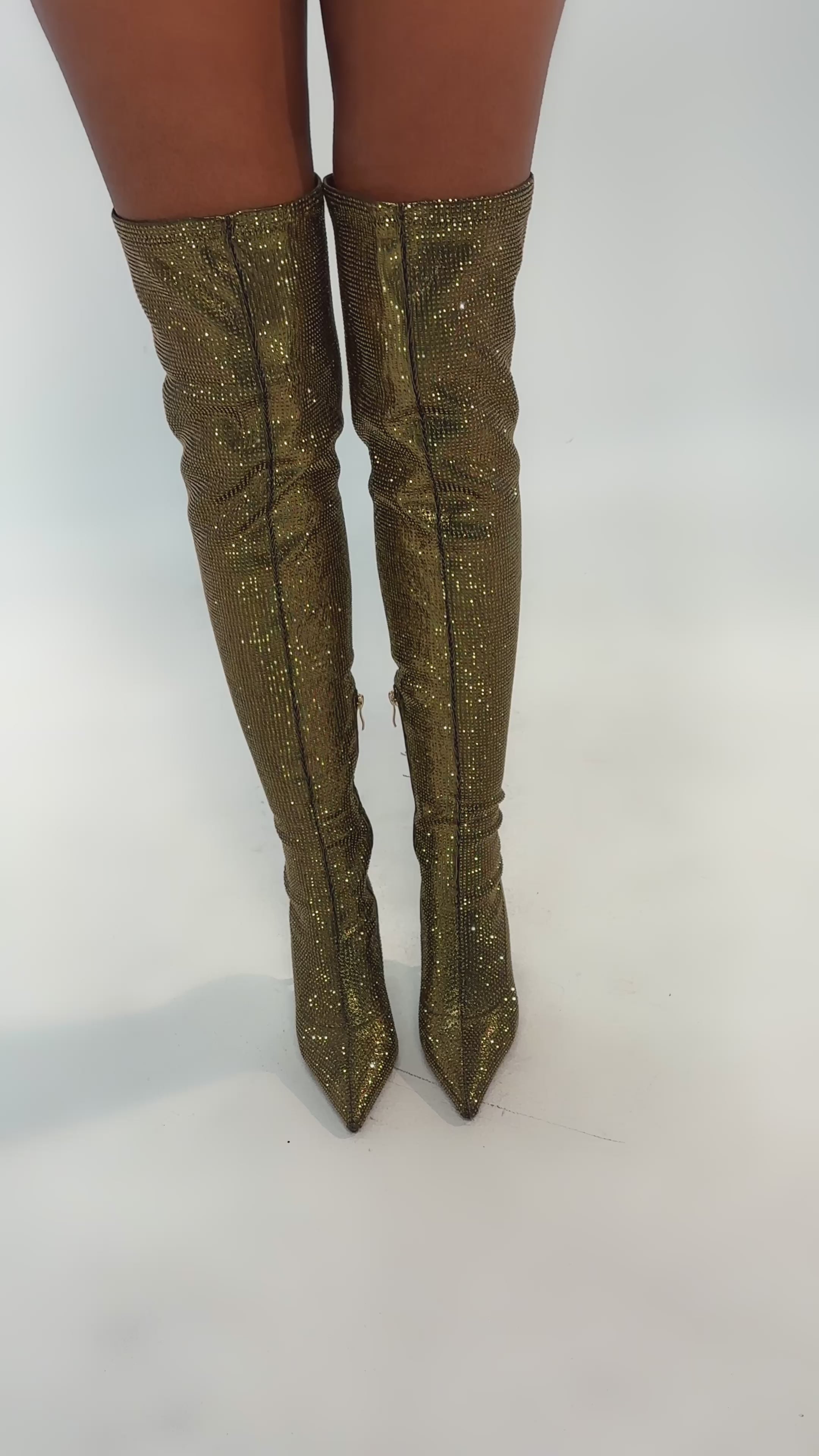 Video of woman modeling the AKIRA GOLD SELMA GOLD SPARKLE OVER THE KNEE BOOT, featuring stiletto heels, pointed toes, and glittery gold material that reflects light for a shiny, glamorous look.