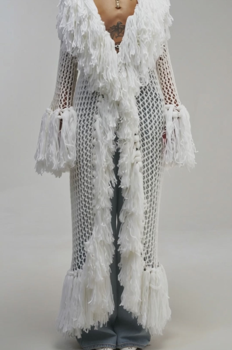 Video of a woman modeling the SOFT DRAMA FRINGE CARDIGAN—styled as a cozy, chic knit longline cardigan with white crochet fringes.
