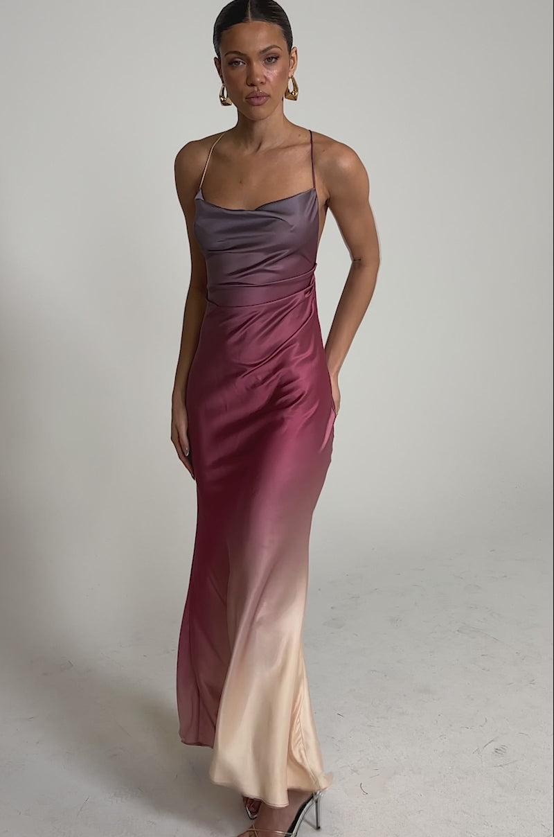A video of a woman wearing the PRETTY WOMAN MAUVE MAXI DRESS, a sleeveless, floor-length satin gown with thin straps and an ombre gradient fading from purple to pink and light beige.