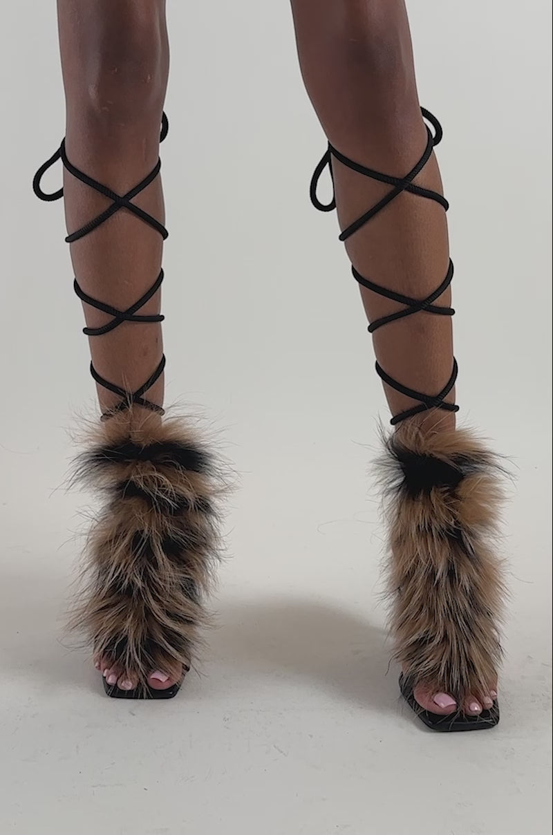 Video of a woman modeling the AKIRA GOLD ORLA BLACK MULTI FUR ROPE STILETTO SANDAL—lace-up high heels with faux fur accents.