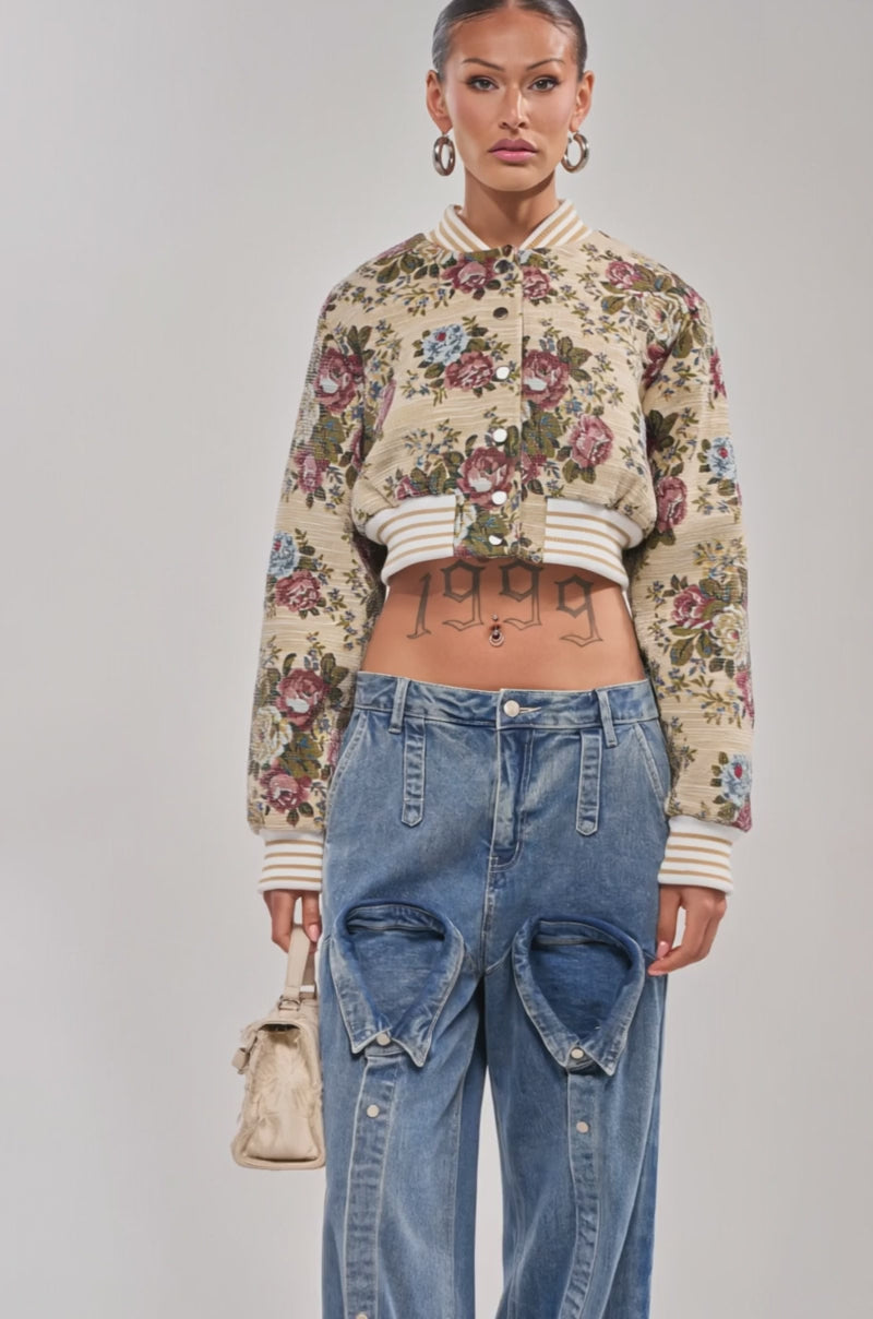 Video of woman modeling the NOT YOUR AVERAGE TAPESTRY BOMBER over a white crop top and blue jeans, accessorized with large hoop earrings. 