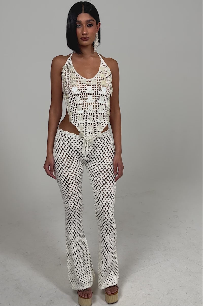 Video of woman modeling the BEACH VIBES CROCHET FLARED PANT with a matching cream crochet top and beige platform sandals.