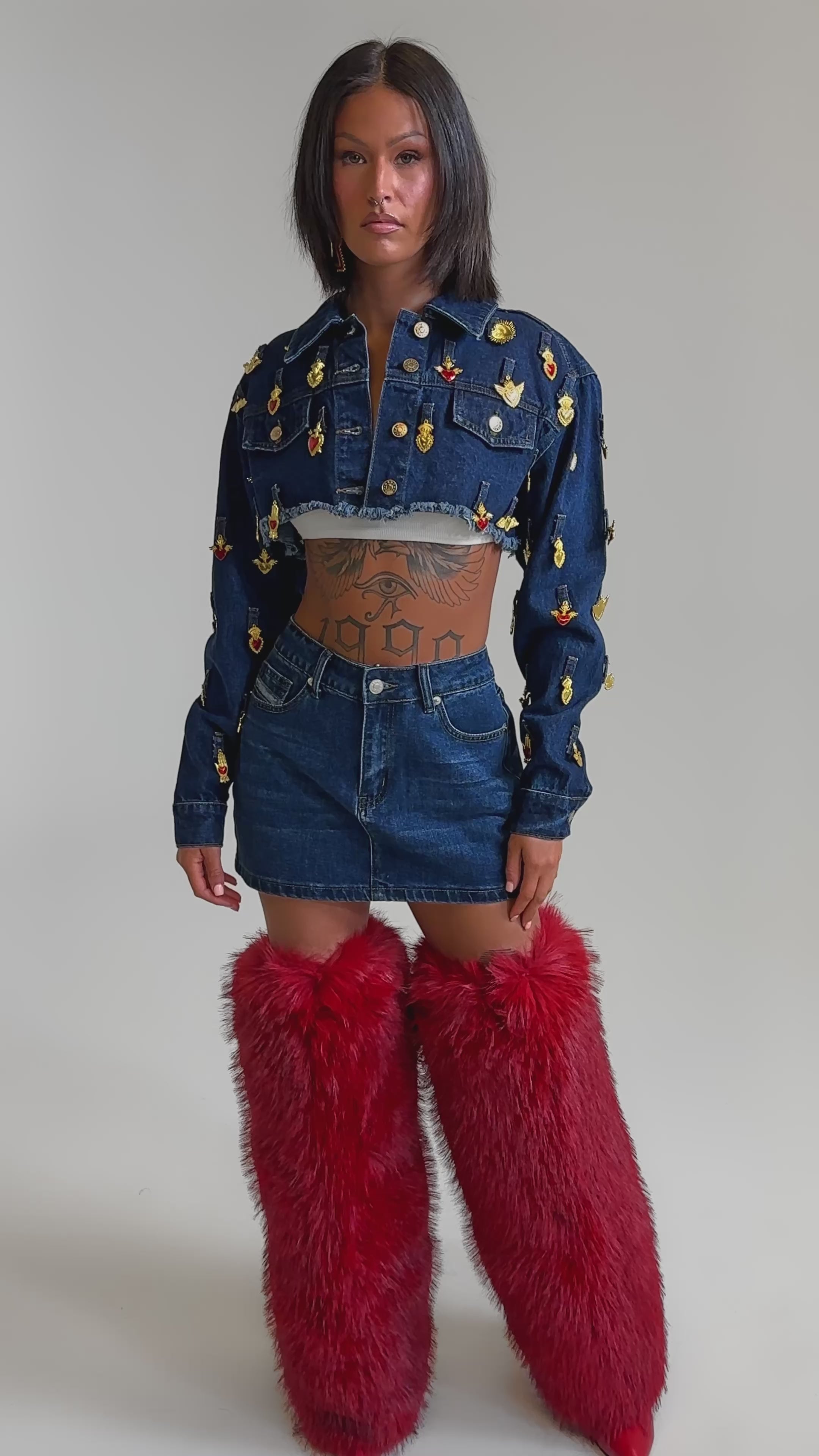 A video of a woman in the JUST A CRUSH CROPPED DENIM JACKET with a coordinating mini skirt and tall red fur boots.