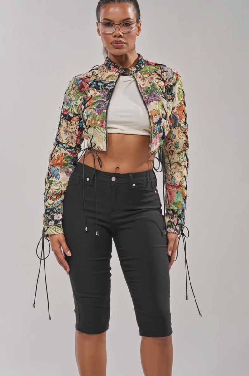 Video of woman modeling the TELL ME ABOUT IT PATCHWORK MOTO jacket and high-waisted black pants, standing against a plain light background.